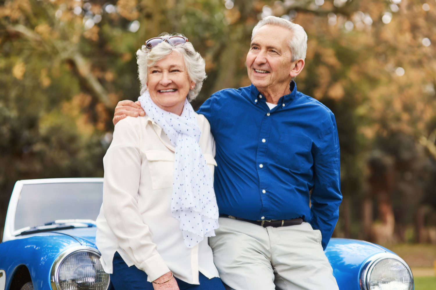 Senior couple enjoying a road trip in a classic blue sports car